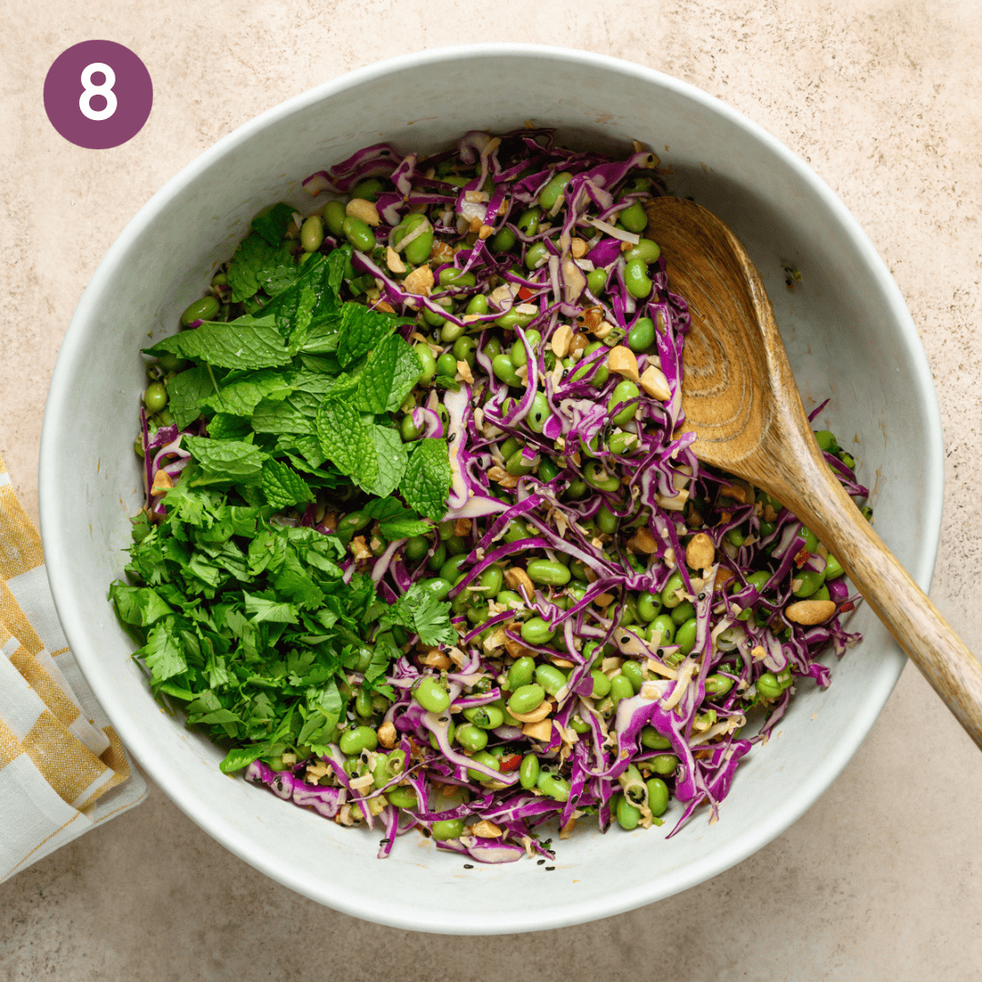 Finished salad with cilantro, mint and a large spoon in a bowl.