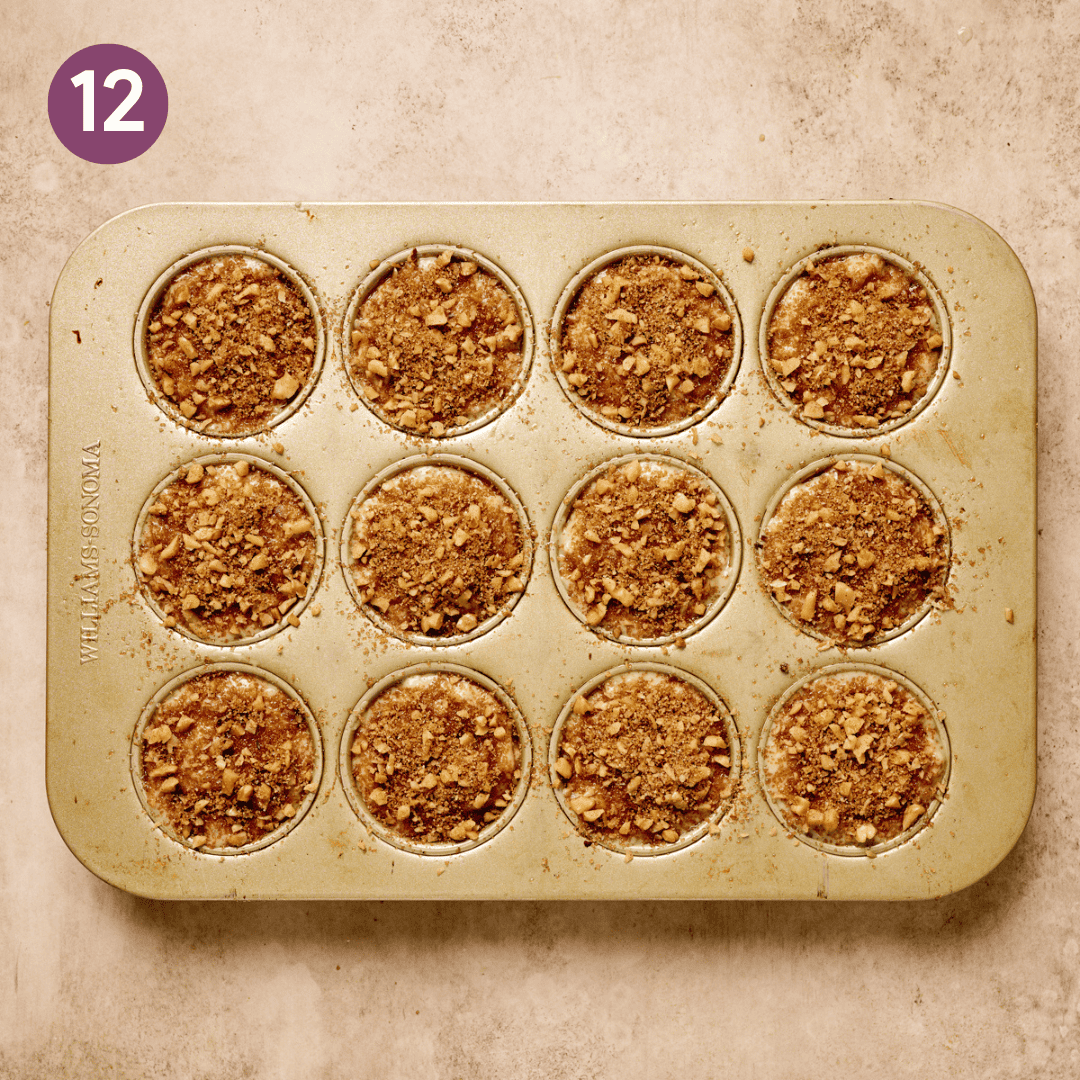 Walnut crumble sprinkled over top of each muffin in muffin tray.