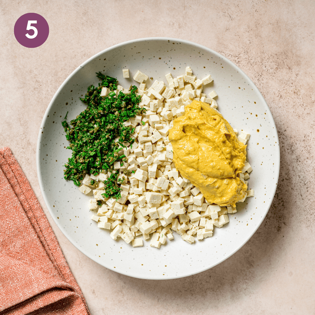 egg salad sauce, tofu and herbs in a bowl before being combined.