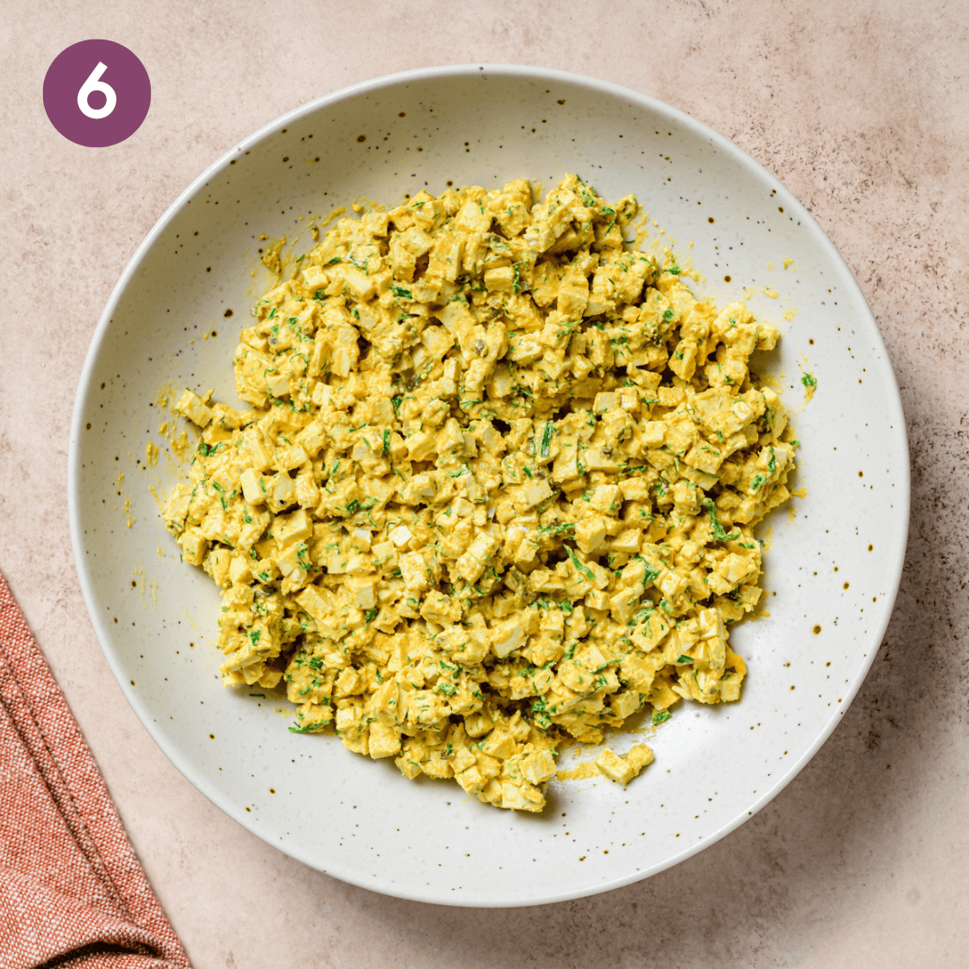 egg salad sauce, tofu and herbs in a bowl after being combined.