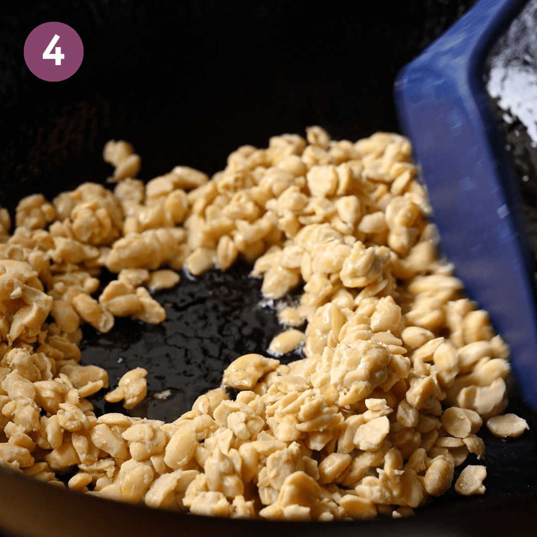 person beginning to cook crumbled tempeh in a skillet.