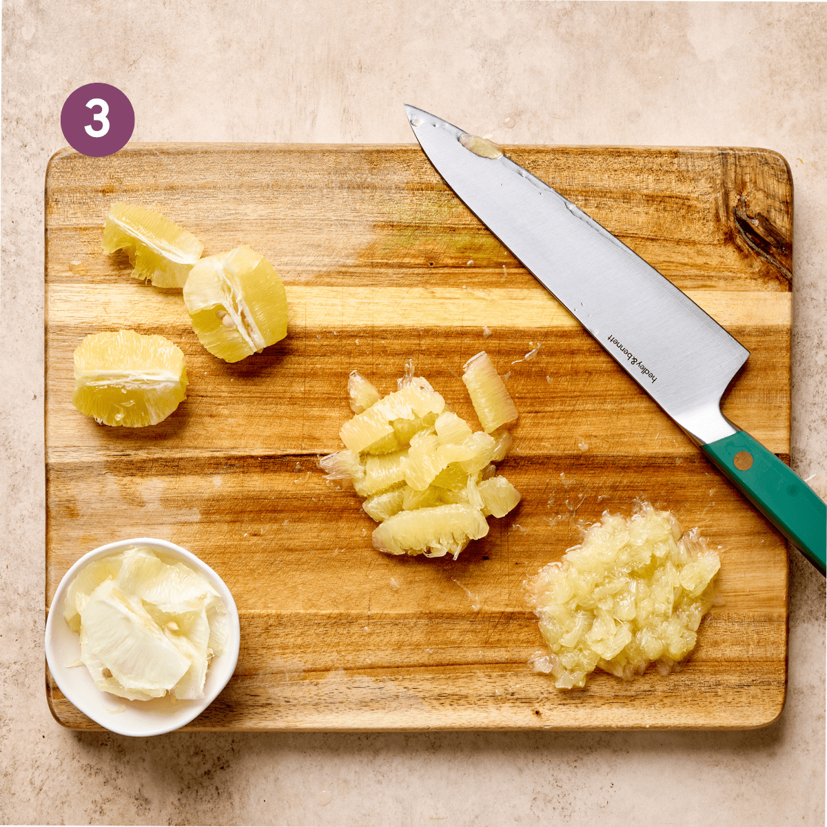 peeled lemon wedges and chopped lemon pieces on a wooden cutting board with a green knife.