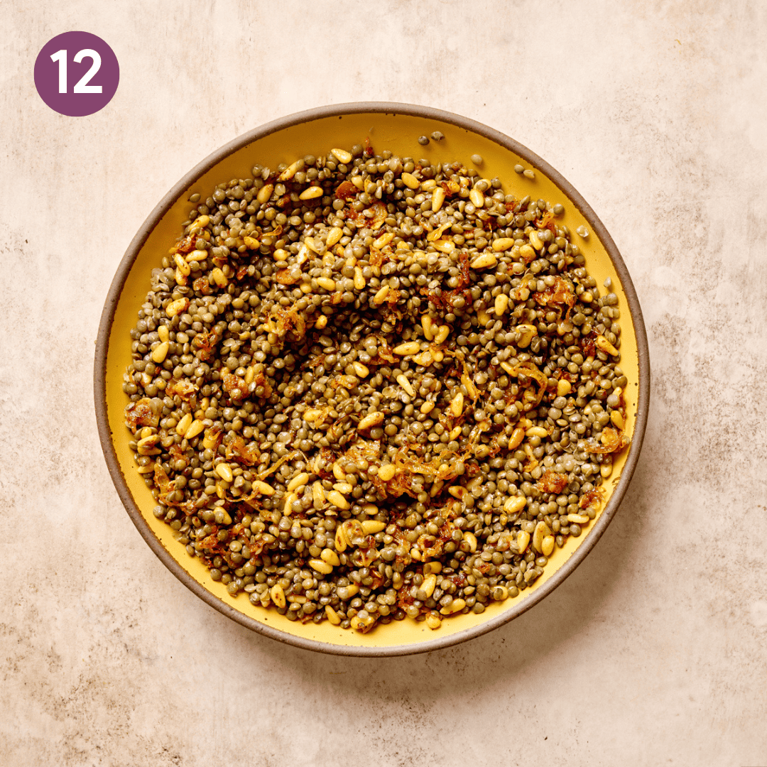Lentils and pine nut aromatic mixture in yellow bowl.