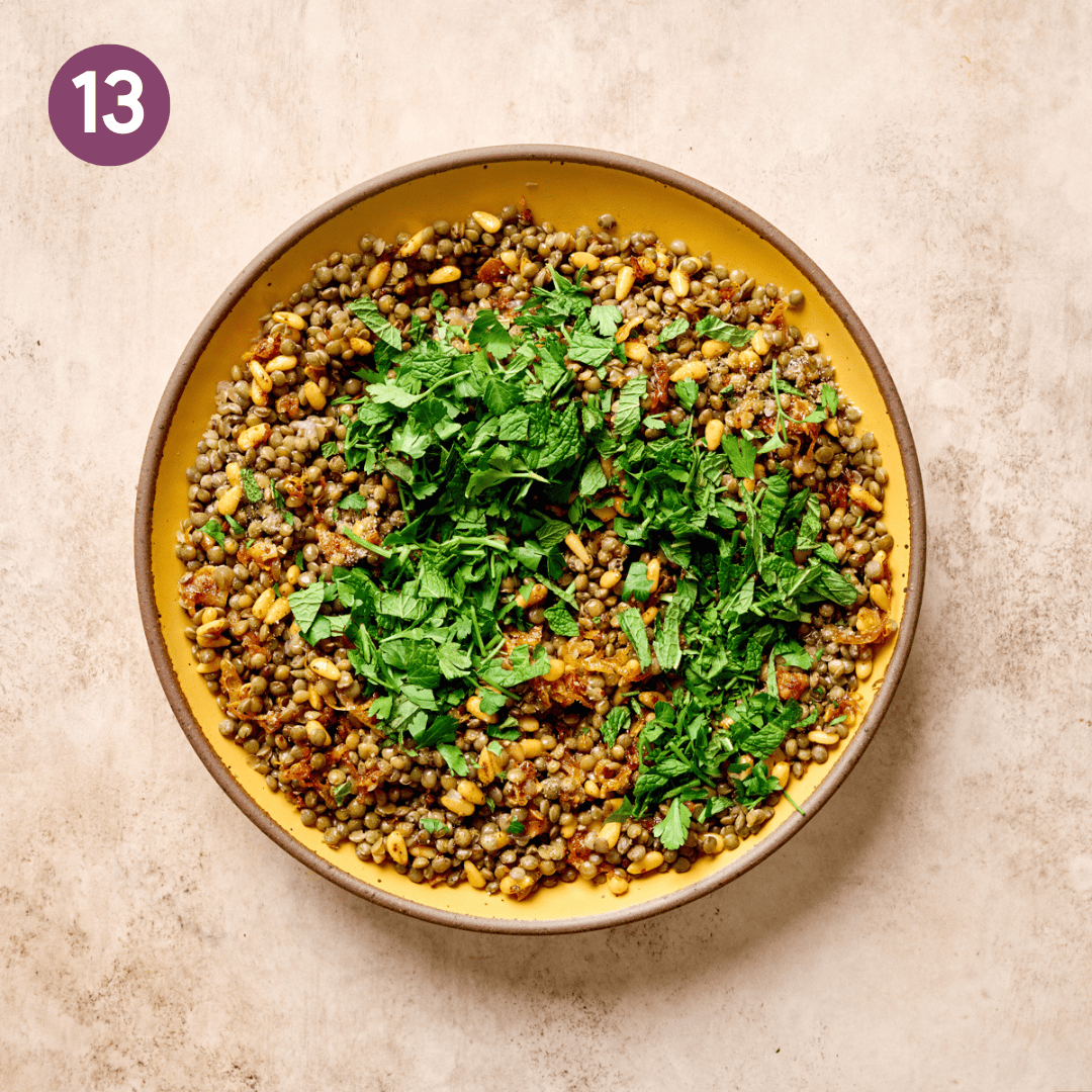 Herbs added on top of lentil pine nut mixture in bowl.
