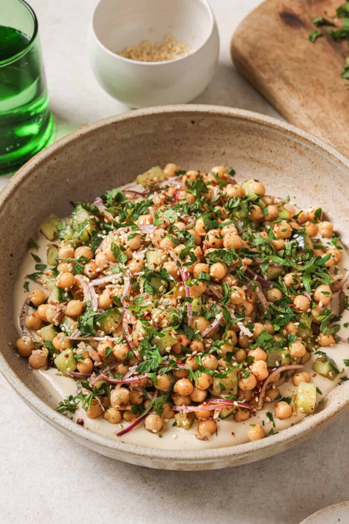 Angled overhead shot of chickpea salad in a beige bowl with a spoon.