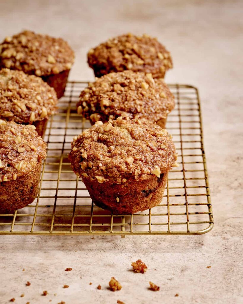 Walnut crumble sprinkled over top of each muffin in muffin tray.