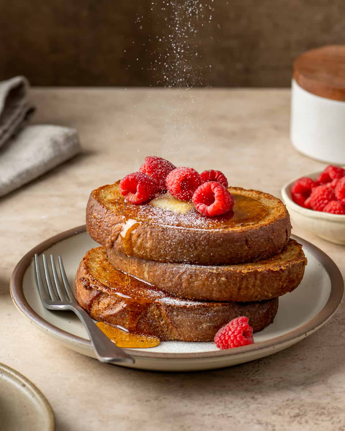 Side view of someone pouring maple syrup on two slices of vegan french toast.